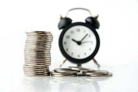 A stack of coins and a clock on a white background. Composition with selectiv Stock Photos