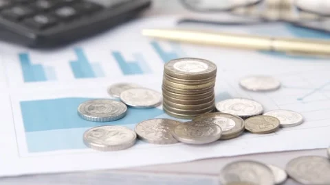 Stack of coins and financial documents on table with calculator and pen. Stock Footage 333031396