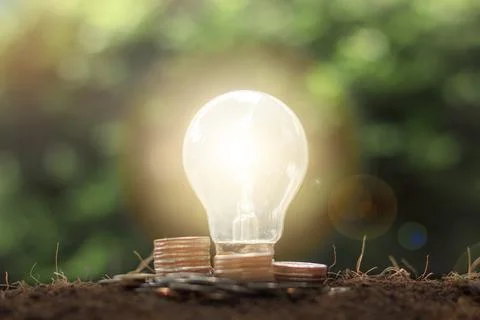 Stack of coins and money with light bulb energy saving concept.  Saving, acco Stock Photos