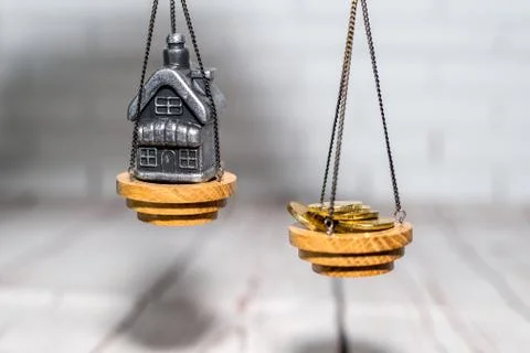 Stack of coins and a small house on the scales. The concept of choice, cash Stock Photos