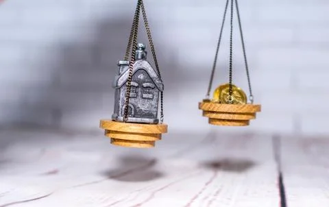 Stack of coins and a small house on the scales. The concept of choice, cash Stock Photos