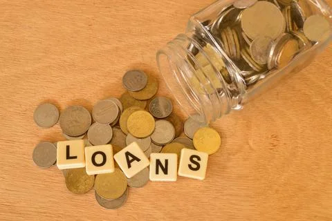 Stack of coins and square letters with text LOANS. Financial concept. Stock Photos