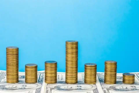 Stack coins on the background of banknotes. Dynamically changing graph. Stock Photos