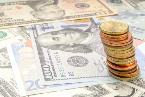 Stack of coins on background of various Euro and Dollar banknotes Stock Photos