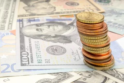 Stack of coins on background of various Euro and Dollar banknotes Stock Photos