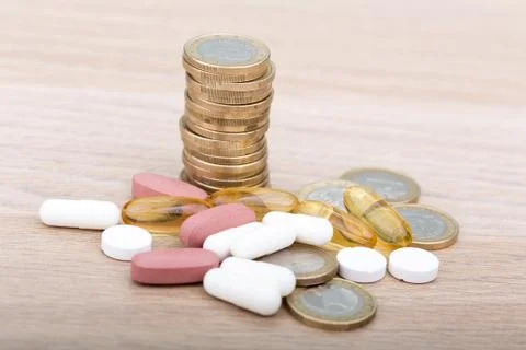 Stack of coins between capsules and pills Stock Photos