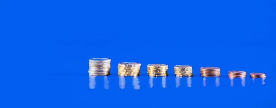 Stack of coins on blue background with copy space. Business growth and financ Stock Photos