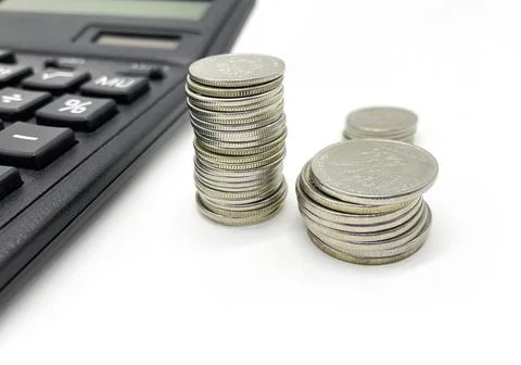 A stack of coins with a calculator on an isolated white background. Stock Photos
