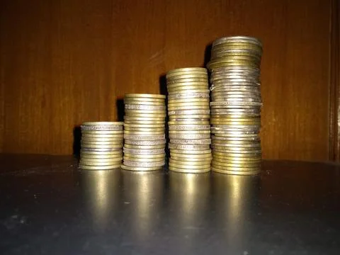 Stack of coins on glass table with reflection in front of mirror. Stock Photos