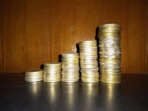 Stack of coins on glass table with reflection in front of mirror. Stock Photos