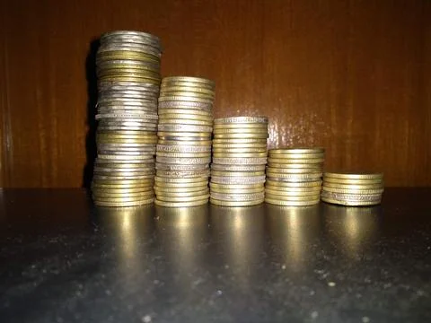 Stack of coins on glass table with reflection in front of mirror. Stock Photos