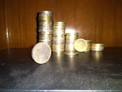 Stack of coins on glass table with reflection in front of mirror. Stock Photos