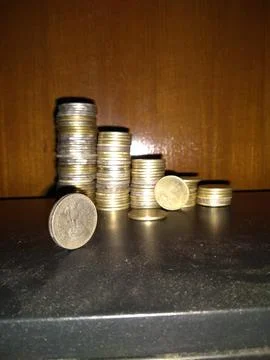 Stack of coins on glass table with reflection in front of mirror. Stock Photos