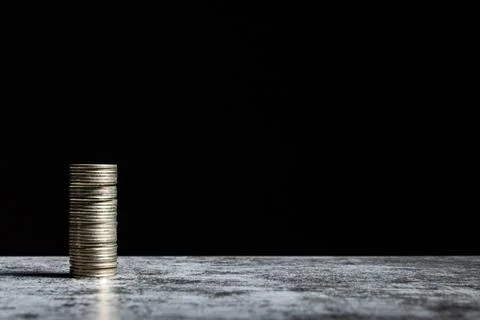 Stack of coins on grey table and black background with copy space Stock Photos