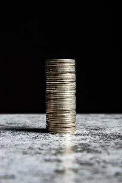 Stack of coins on grey table and black background Stock Photos