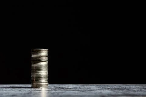 Stack of coins on grey table and black background. Start-up capital concept with Stock Photos