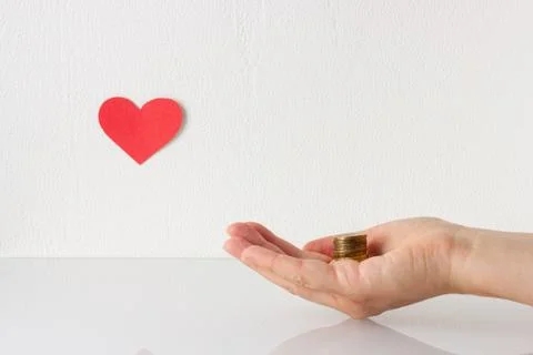Stack of coins on hand and red heart symbol on the white background. Donation Stock Photos