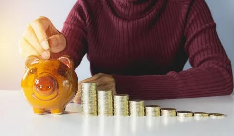 Stack coins with hand of female drop the coin into piggy bank. Financial and  Foto stock