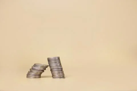 A stack of coins on a light yellow background. Investment concept Stock Photos