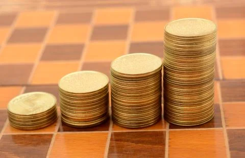Stack of Coins making Growth graph on chess board Stock Photos