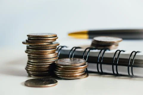 A stack of coins next to a notepad. Budget planning. Foto stock