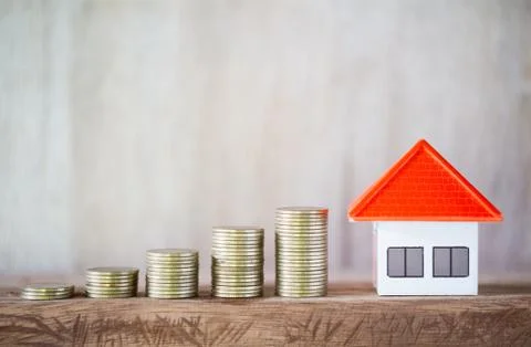 Stack of coins In order from low to high.And an orange roof model house on a  Stock Photos