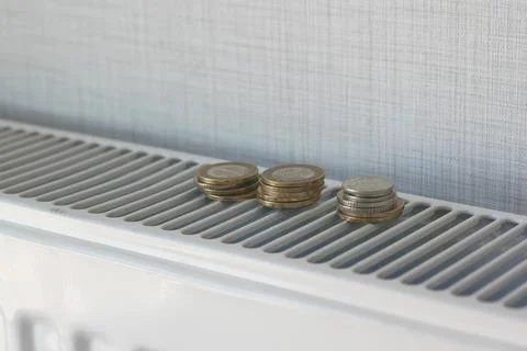 Stack of coins on radiator To Save On Energy Bill 库存照片