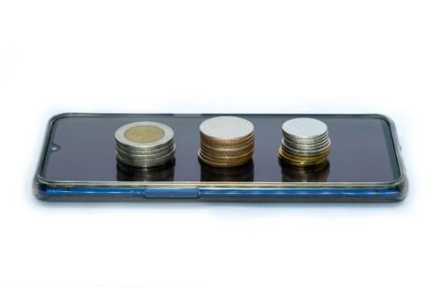 Stack of coins on smart phone isolated on white background - business finance Stock Photos