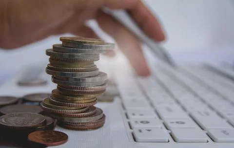 Stack coins on white laptop and finger press button on keyboard. Financial an 库存照片
