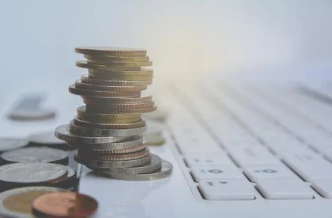 Stack coins on white laptop, computer. Financial and saving concept. 库存照片