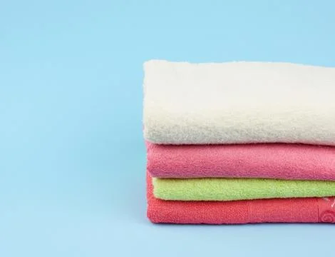 Stack of colored cotton terry folded towels on a blue background Stock Photos