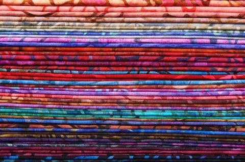 Stack of colorful batik fabrics as a vibrant background image Stock-Fotos