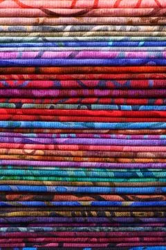 Stack of colorful batik fabrics as a vibrant background image Stock Photos