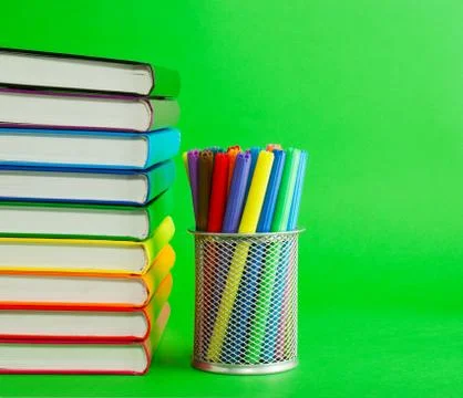 Stack of colorful books and socket with felt pens Stock Photos