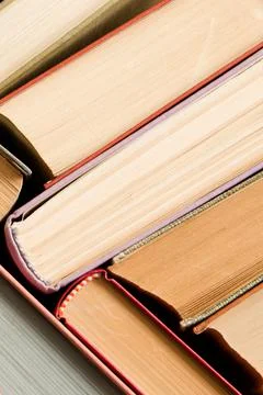 A stack of colorful books in a library or a room. Many multi-colored thick bo Stock Photos
