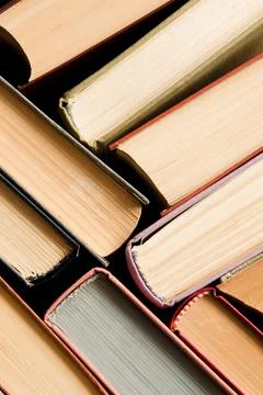 A stack of colorful books in a library or a room. Many multi-colored thick bo Stock Photos