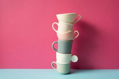 Stack of colorful coffee cups on skyblue table. pink wall background Stock Photos