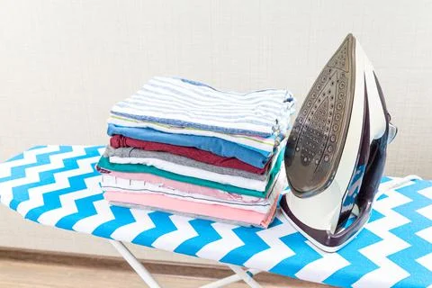 Stack of colorful cotton clothes and iron.Household laundry ironing. Stock Photos