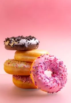 Stack of colorful donuts on pink background. Stock Photos