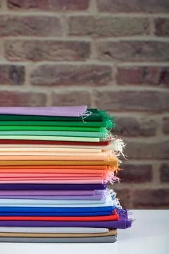 Stack of colorful fabrics on brick wall background, space for text 스톡 사진