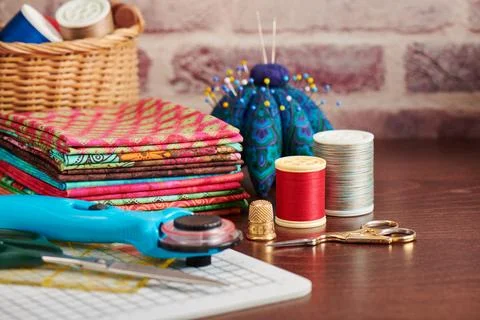 Stack of colorful fabrics on table surrounded by sewing accessories on bric.. Foto stock