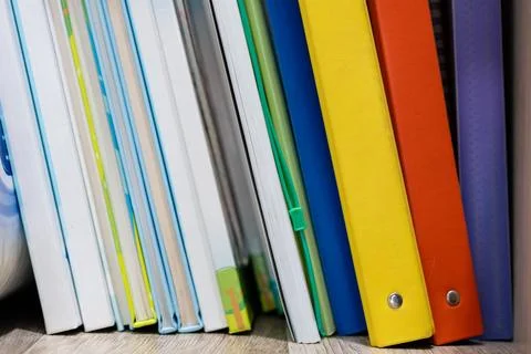 A stack of colorful files and documents on a shelf in an office Stock Photos