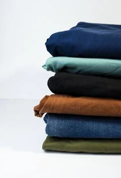 Stack of colorful folded pants on clean white background Stock Photos