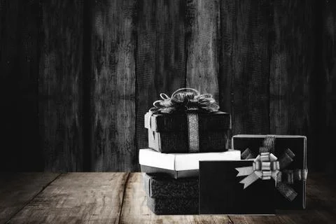 Stack of colorful gift box with black ribbon on wooden background Stock Photos