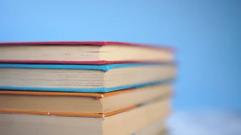 Stack of colorful hardback books on a blue bright background Stock Footage 128682562