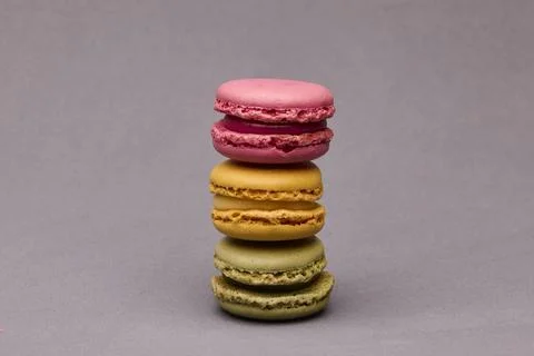 Stack of colorful macarons pink yellow green on gray background Stock Photos