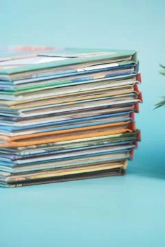 Stack of colorful magazines resting on a light blue surface Stock Photos