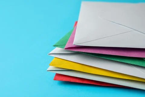 Stack of colorful paper envelopes on light blue background, closeup. Space fo 写真素材