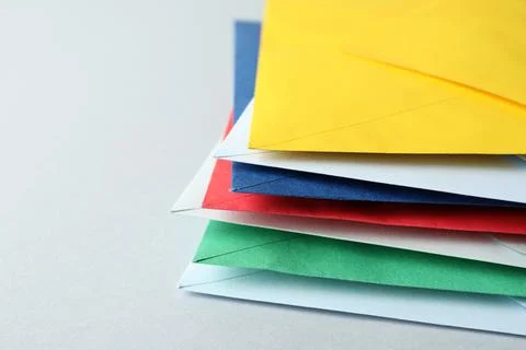Stack of colorful paper envelopes on light background, closeup Foto stock