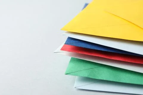 Stack of colorful paper envelopes on light background, closeup. Space for tex Foto stock